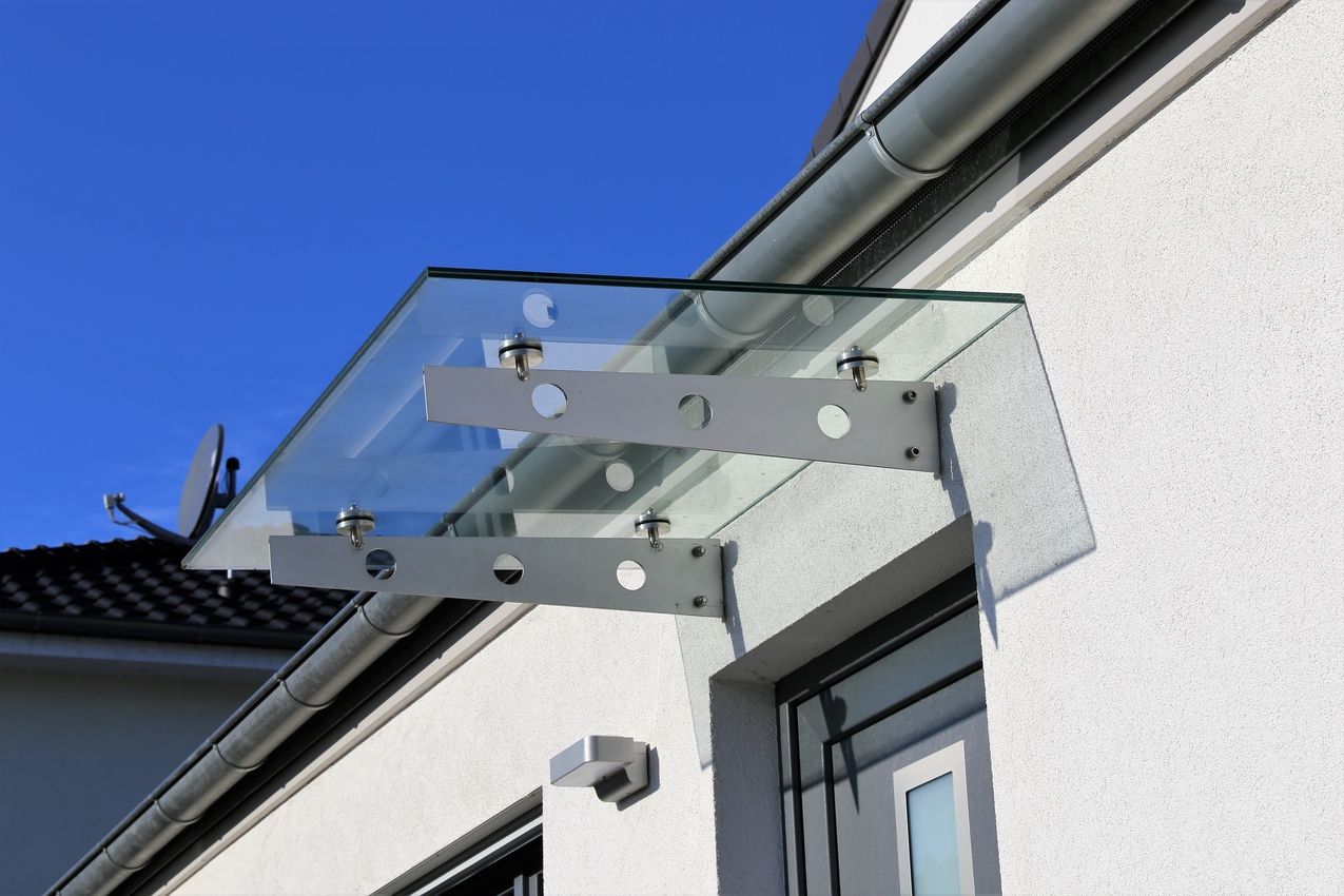 Glasvordach mit Metallbefestigungen über einem Hauseingang